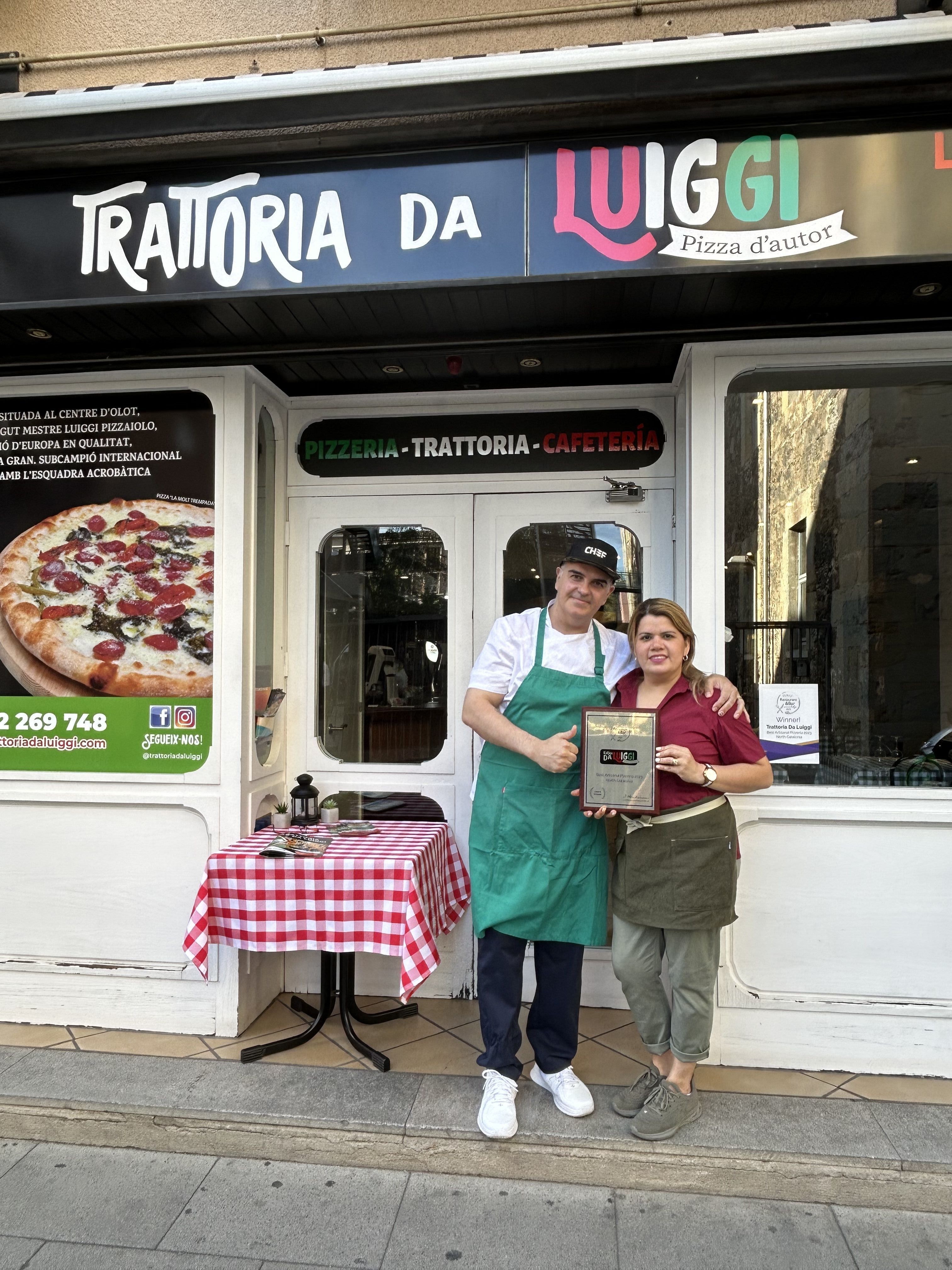 En Luiggi i la Saira davant de la trattoria amb la placa del premi LUXlife
